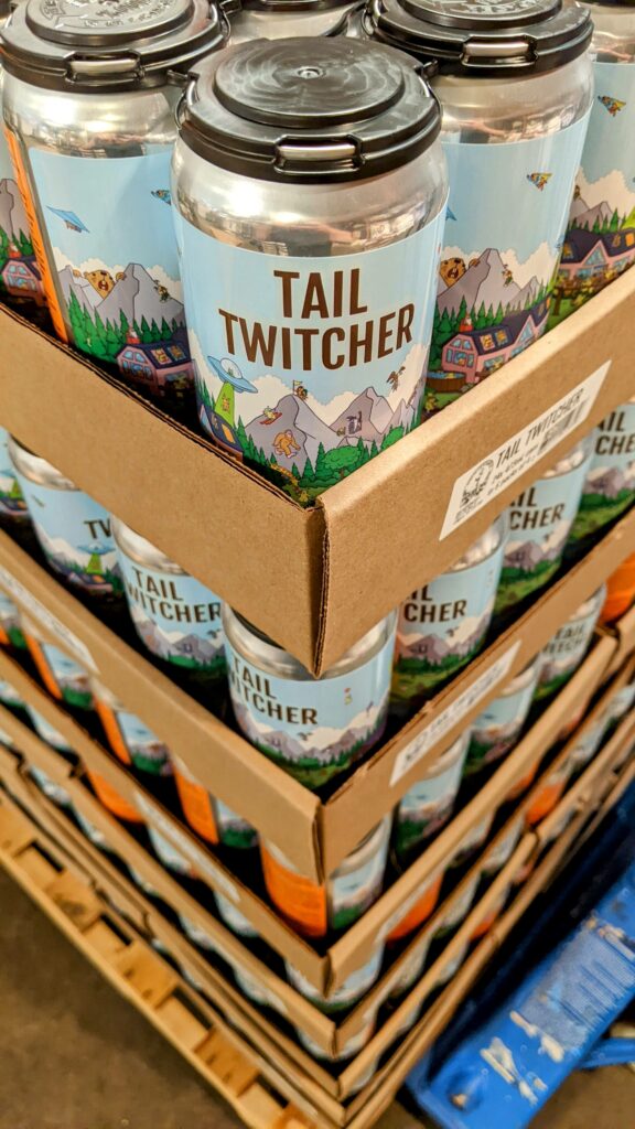 A corner view of a fully-stacked skid of Tail Twitcher cans in cardboard flats, ready to ship to Liquor Connect.