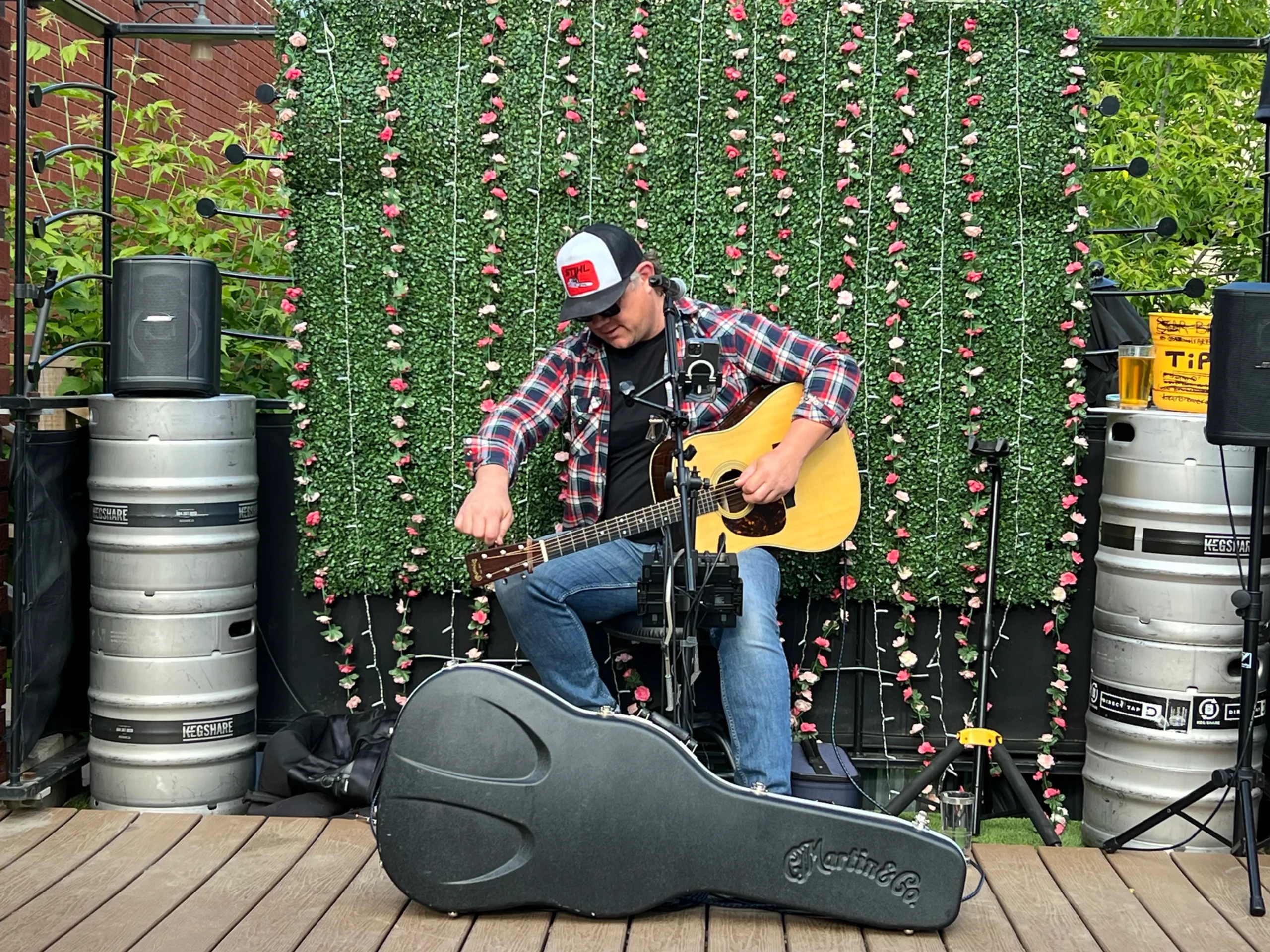 Musician Bear Brewer tuning up his guitar while playing on an outdoor patio.