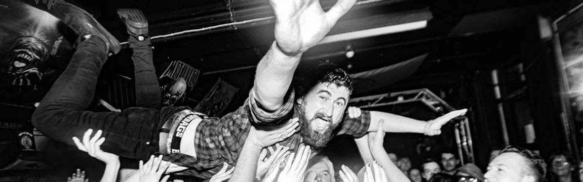 Calgary-area musician Jamie Allanach crowd surfs at a musical show, in black and white.