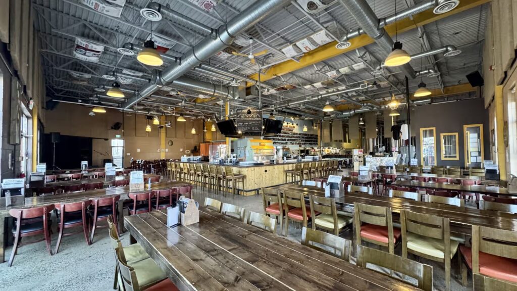 A wide-angle view of Prairie Dog Brewing's restaurant dining room from the northwest corner, featuring the large communal tables found in our "Beer Square" and "L" sections, as well as our large central bar.